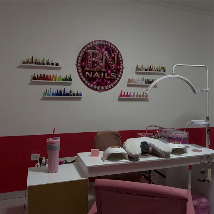 Parede do studio BN Nails com o logo da marca e prateleiras de esmaltes coloridos